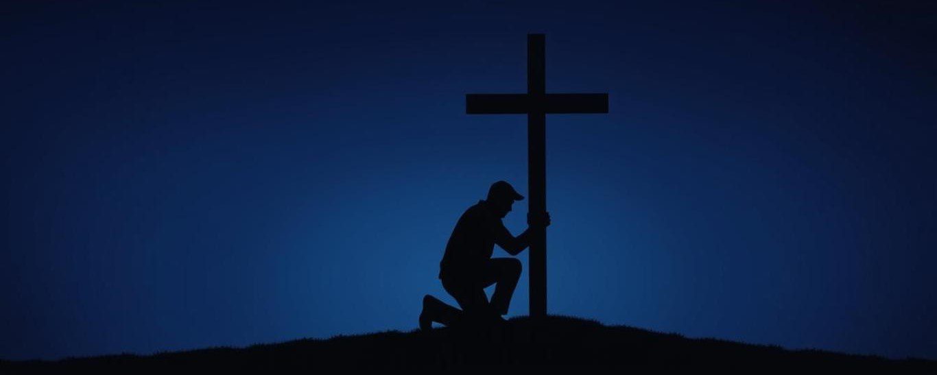 The silhouette outline of a man kneeling before a Christian cross